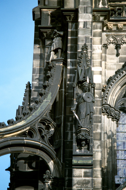 A statue of a woman holding a round shield and a sword on the side of the Scott Monument 