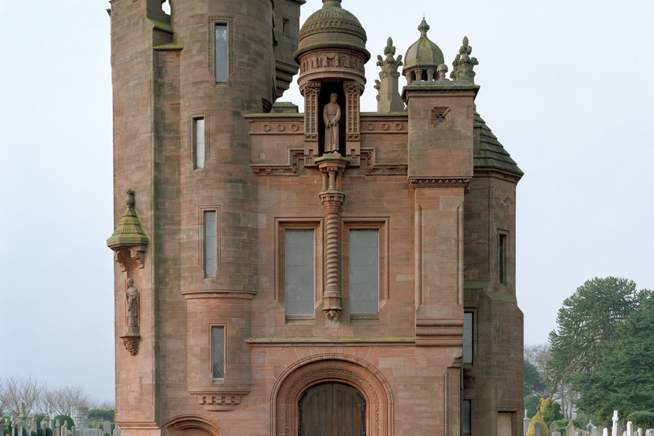 A Scots Baronial building with towers and a central statue