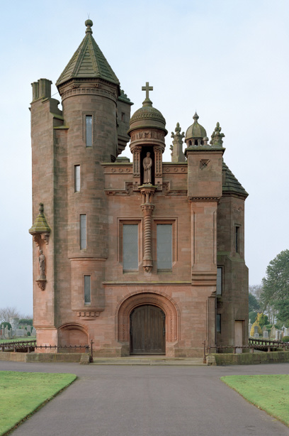 A Scots Baronial building with towers and a central statue