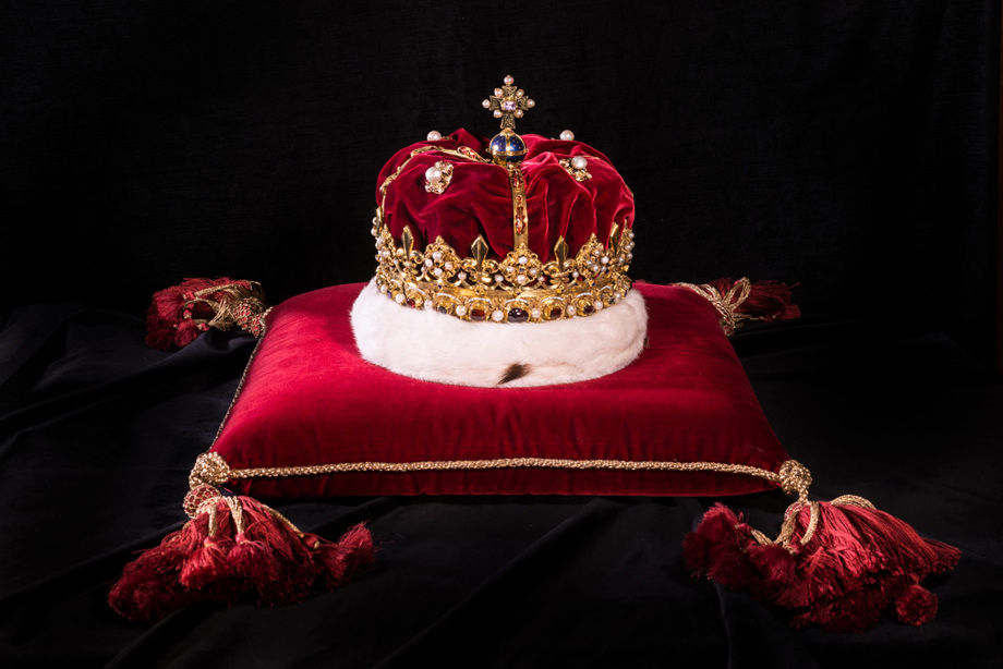 A heavily embellished gold crown sits on a cushion