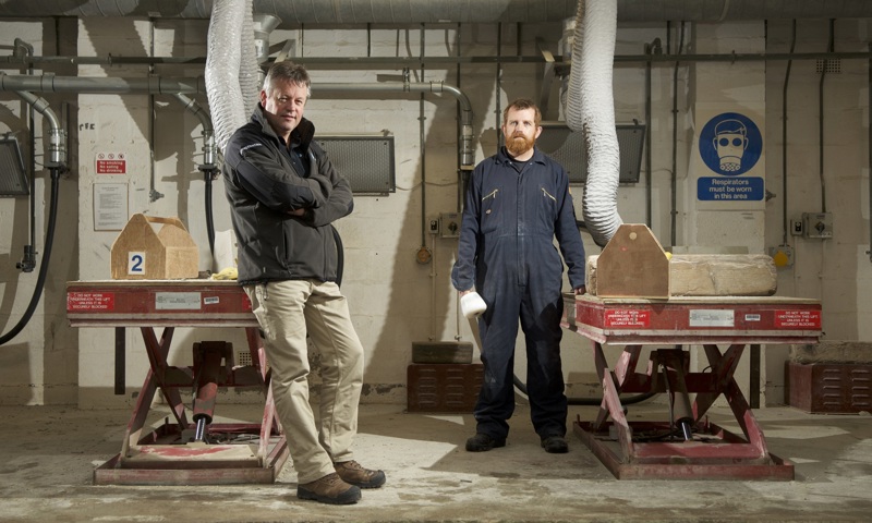 Two people standing inside a stonemasonry workshop