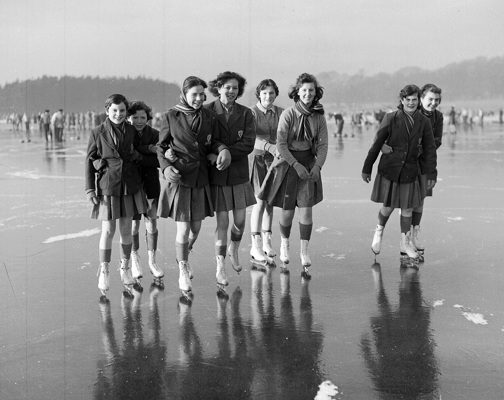 A group of teenage girls wearing school uniforms skating on a frozen loch