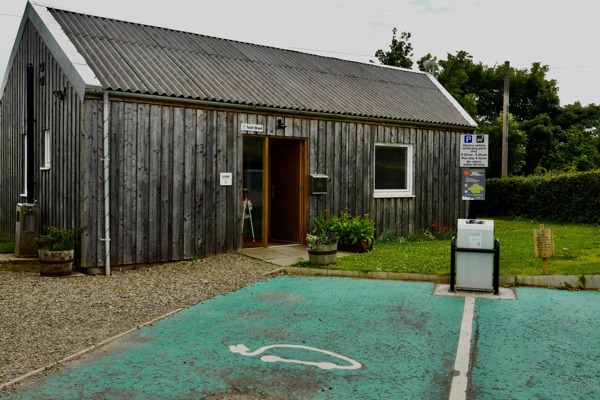 A wooden building and an electric car charging point