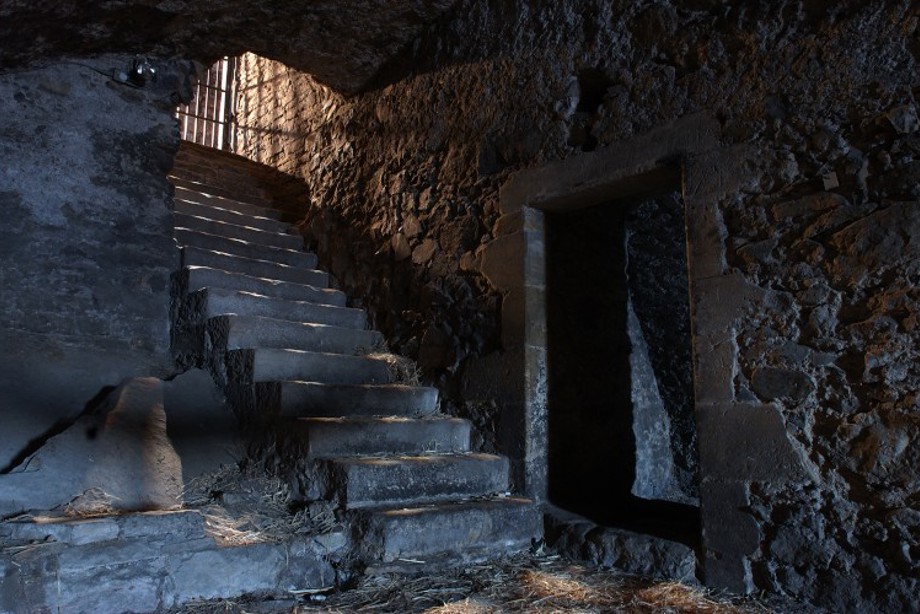 Image of a dimly lit flight of stone stairs next to a door opening