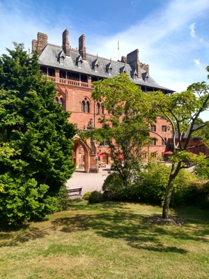 A huge, grand historic house with trees in the foreground 