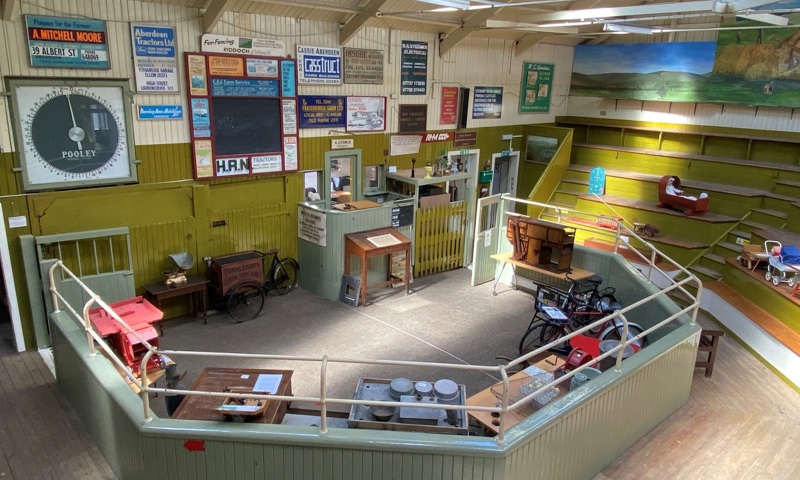 A auction ring surrounded by wooden seating. It was originally used for the sale of cattle but has been repurposed into a museum space displaying various items 