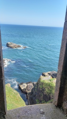 View of the sea, sky and grassy cliff through a ruined stone window place