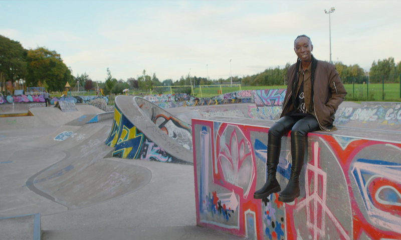 Eunice Olumide sitting on a concrete wall or jump at a skate park