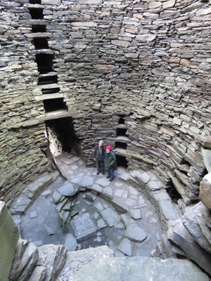 Inside of Mousa Broch showing the curves and incredible stonework. Looking down from high to low with 2 men looking tiny at the bottom of the buildin