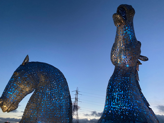 A photograph of the reflection of horse sculptures in water.