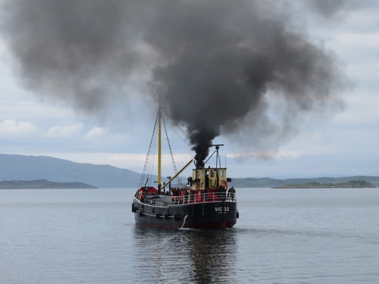 A puffer sailing away from Crinan making a lot of smoke.