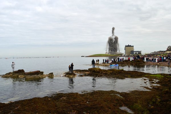 Two large chimneys of a power station being demolished causing the dust to form a figure of a man in the sky.