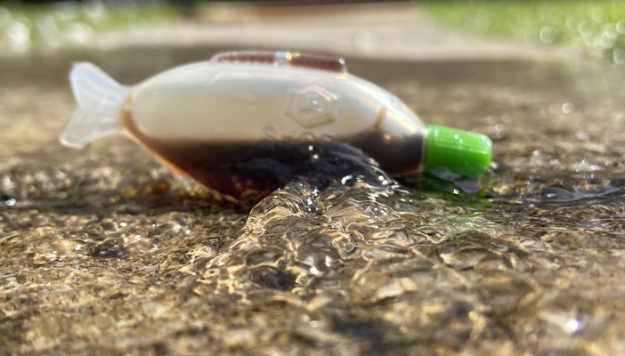 Plastic fish shaped container lays in the water portraying the plastic in our oceans