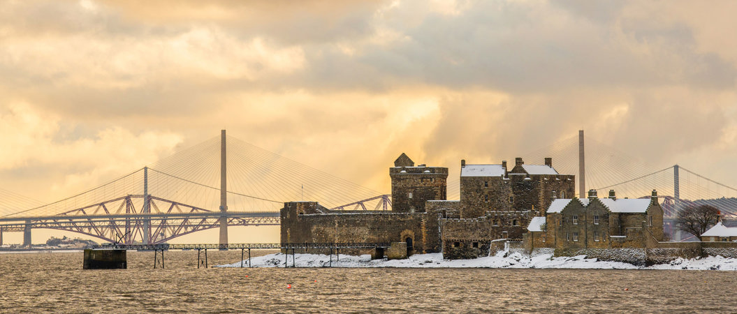 Blackness Castle covered in snow with the Forth Bridges in the background