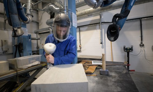 A person carving into a piece of stone in a workshop