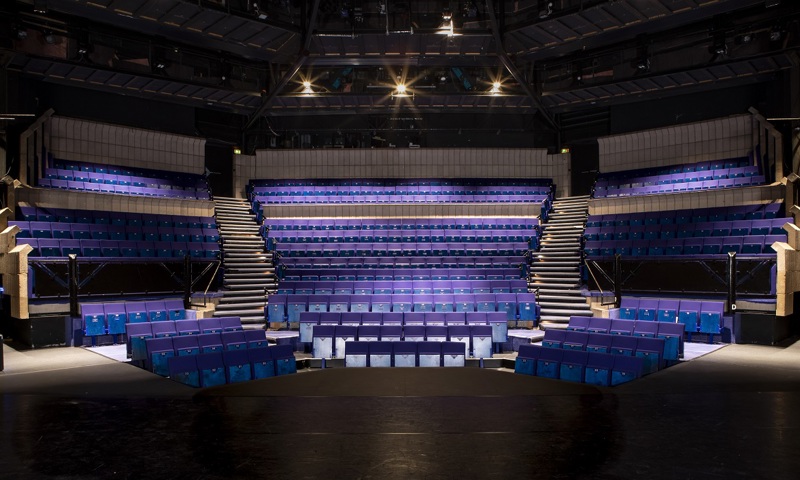 The interior of a modern theatre with purple seats viewed from the stage 