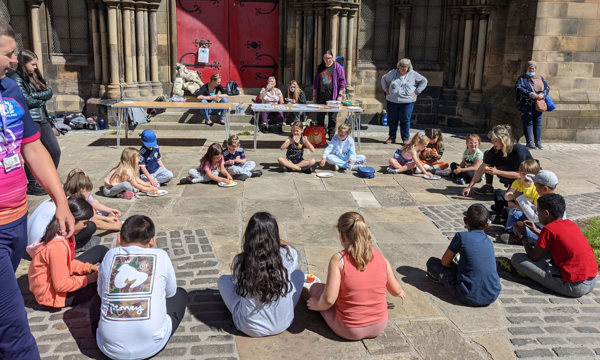 a group of adults and children from Govan Heritage Trust standing and sitting outside a church 