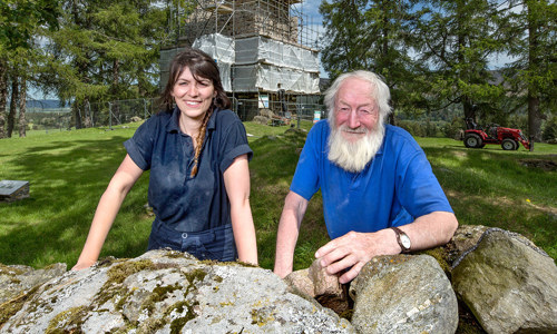 Portrait of two Stonemasons with Knock Castle surrounded in scaffolding behind them 