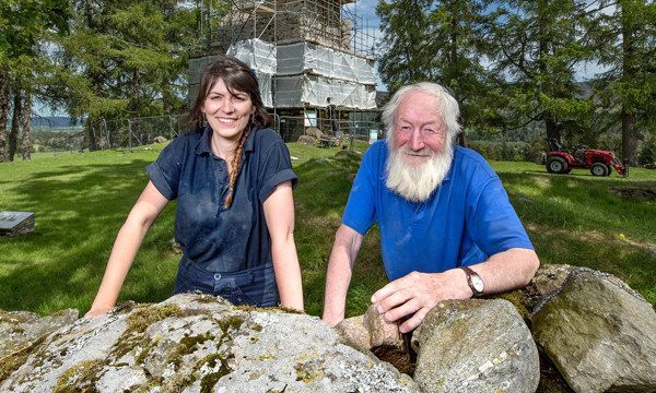 Portrait of two Stonemasons with Knock Castle surrounded in scaffolding behind them 