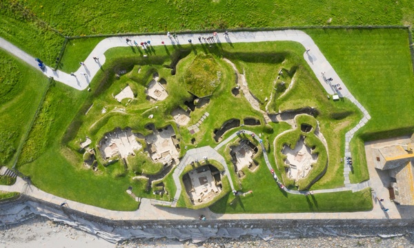 An aerial view of visitors walking above the remains of a Neolithic village