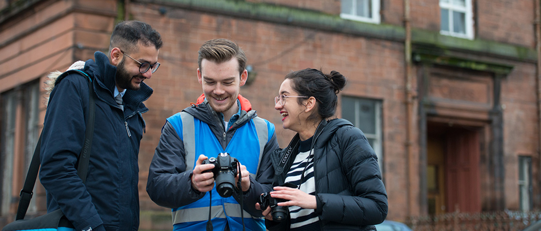 A photographer shows two people a picture he has taken