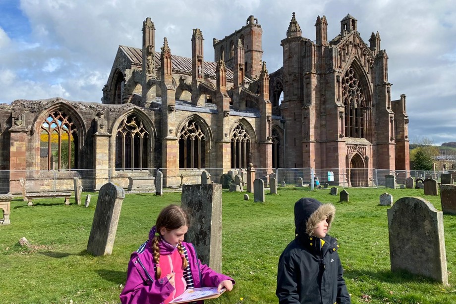 Archie and Maddie draw on paper while visiting Melrose Abbey
