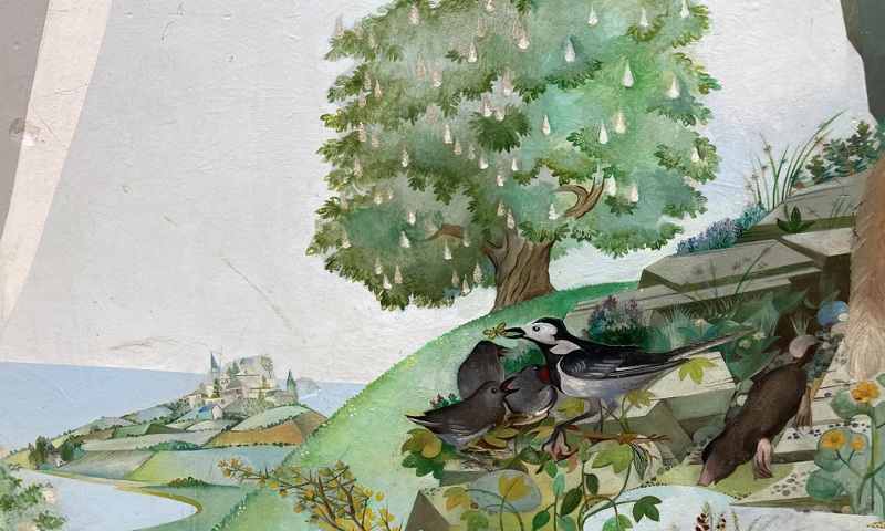 Detail from a colourful mural depicting a rural scene. Birds, a green tree and a distant castle can be seen. 