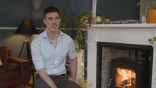 Alasdair Whyte sitting by a fireplace