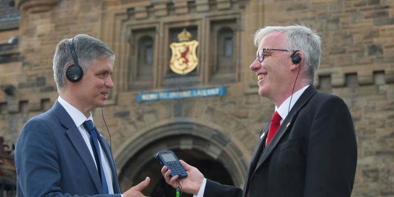 Two people standing in front of Edinburgh Castle listening to an audio guide
