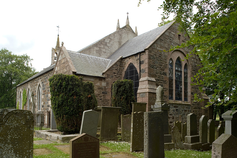 A small stone church with many gravestones outside