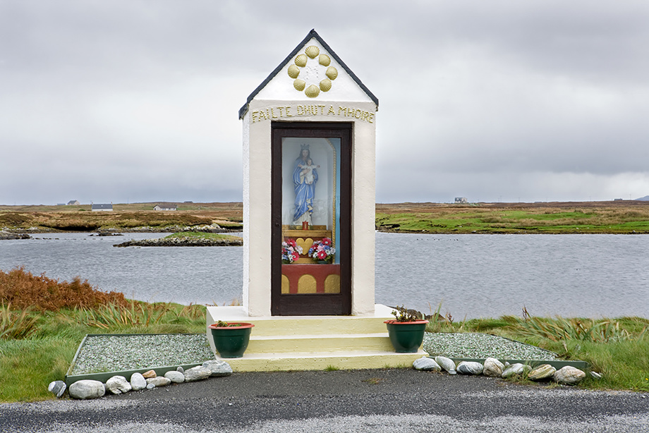 A long, narrow shrine by the roadside, featuring a person holding a baby