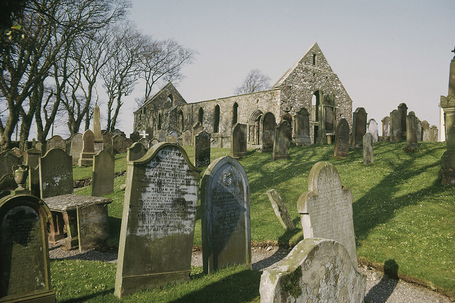 A roofless, stone building with a graveyard in the grounds