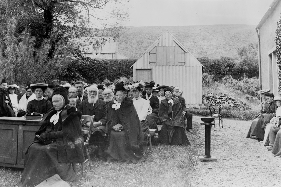 A group of people in formal clothing, sitting in rows of seating outside. Image reference number: 1905 000-000-129-948-R