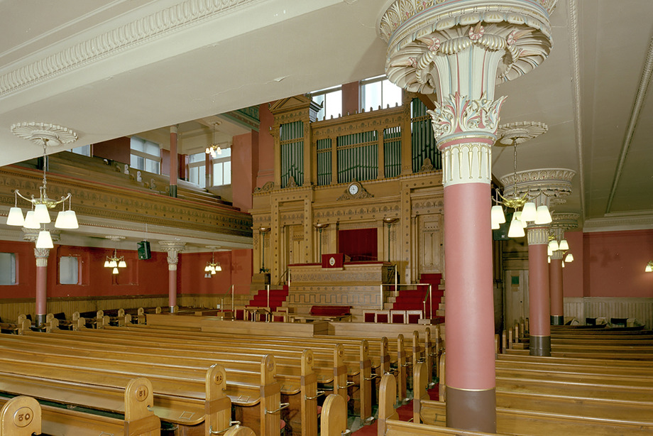 Inside a church with decorative pillars and plasterwork and rows of wooden pews. Image reference: SC_906851