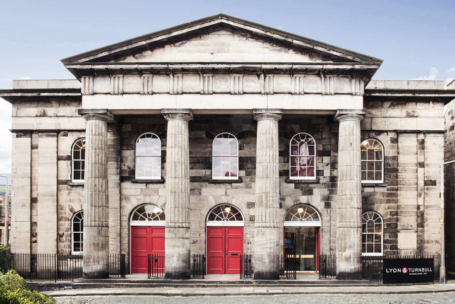 A classical greek style stone building with four columns at the entrance