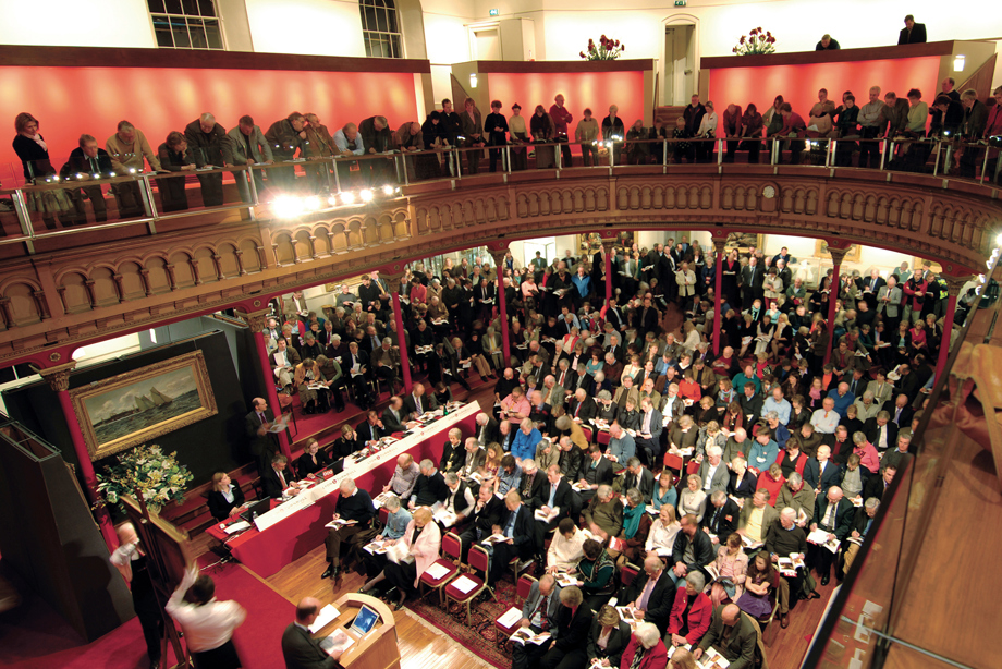 Many people sitting inside a church, and others standing on an upper balcony level