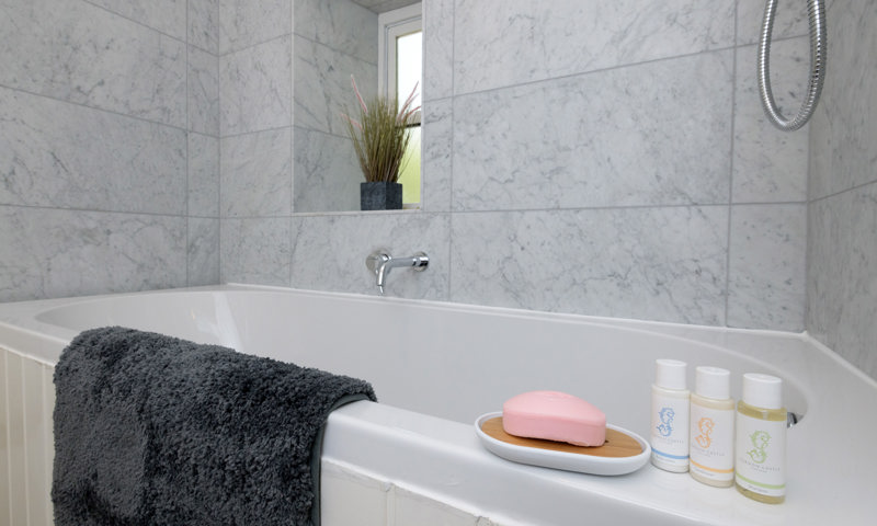 Close up of the bath at Meadowbank Lodge with some toiletries and a bath mat