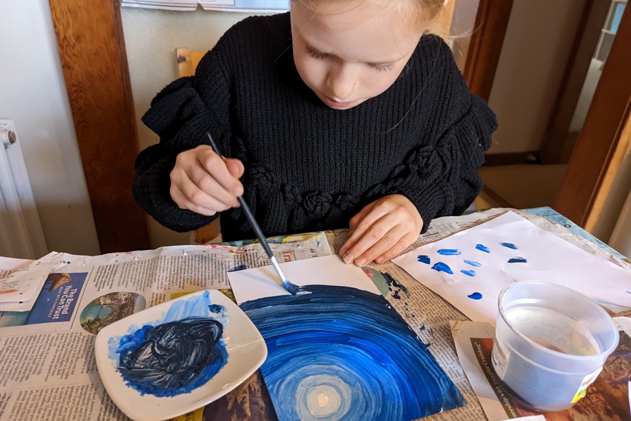 Girl painting moonlit sky at a table