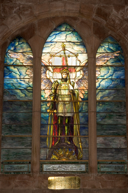 A stained glass window of a winged angel wearing armor