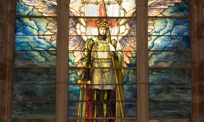 A stained glass window of a winged angel wearing armor