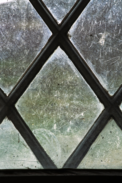 An old window with dates and wording scratched into the glass. Image reference: DP246503 