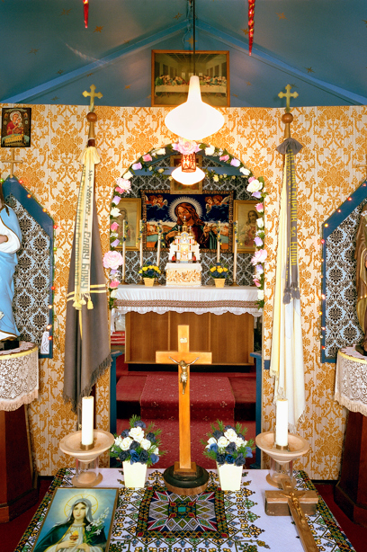 An altar with blue and yellow, busy patterned walls, filled with objects including flowers and crosses. Image reference number: SC_908232