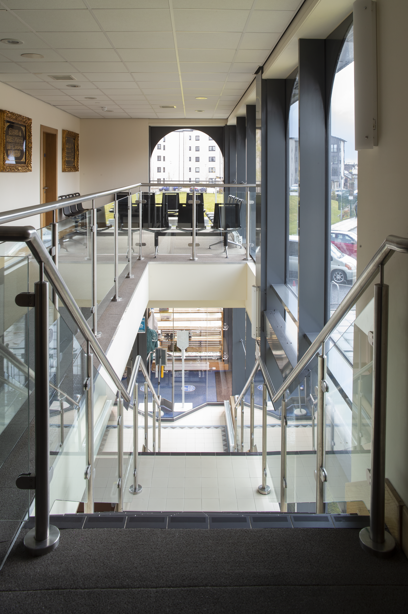 The staircase and hallway area of a mosque with a glass stairway bannister. Image reference number: DP_359541