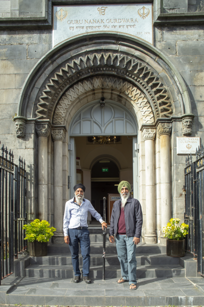 Two people standing outside a building with a decorative sandstone archway. Reference no: DP_374203