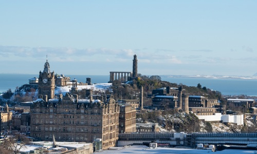View of a distant Calton Hill in the snow with the Forth in the background.