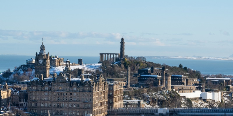 View of a distant Calton Hill in the snow with the Forth in the background.