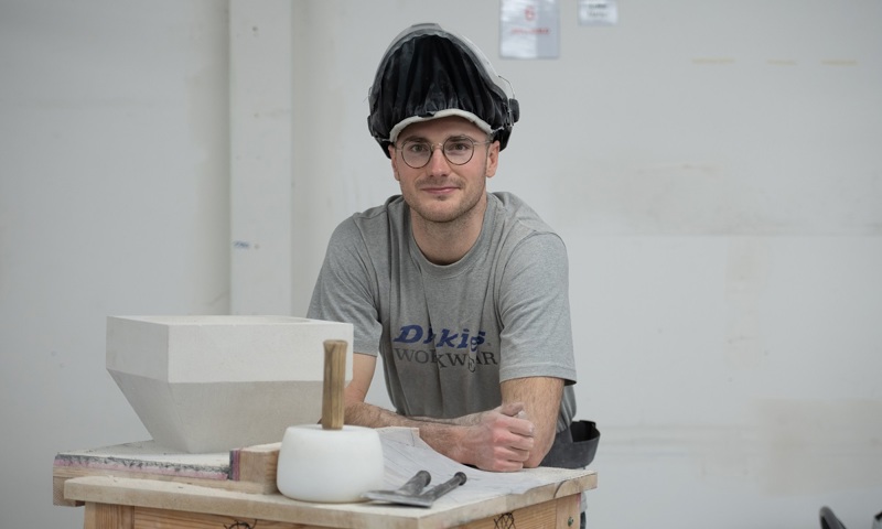 A stonemason standing behind their work bench