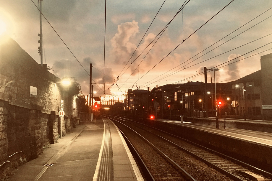 A photograph of Cardross train station at dusk, with the sun setting in the background
