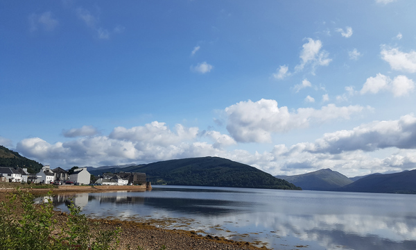 An image of a clear, blue sky and the shores of a loch beside Inveraray