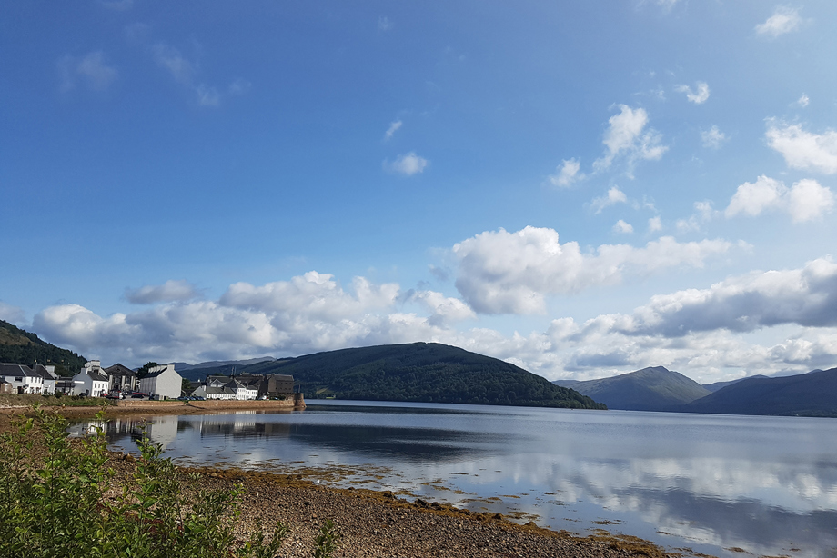 An image of a clear, blue sky and the shores of a loch beside Inveraray